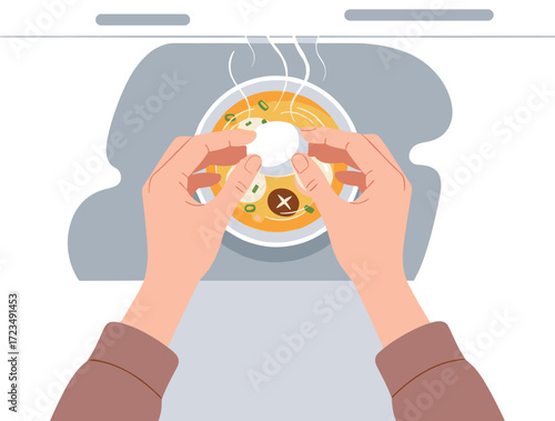 Hands placing dumpling in steaming hot soup, comfort food