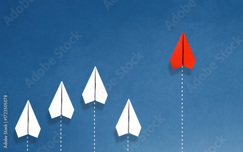 Group of paper plane in one direction and with one individual pointing in the different way on blue background. Business for innovative solution concept.