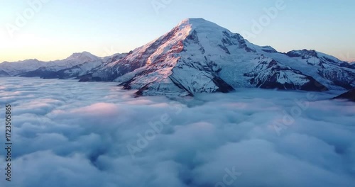 Dramatic interplay of light and shadow on jagged rock formations as golden hour sun illuminates the peak from above the cloud layer. no data