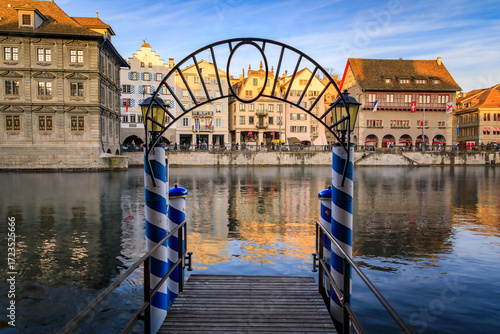 Wall Mural A pier with a decorative arch and blue striped poles on the Limmat River with hi
