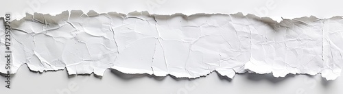 A horizontally-oriented close-up shot of a piece of white crumpled paper with torn edges, set against a plain white background
