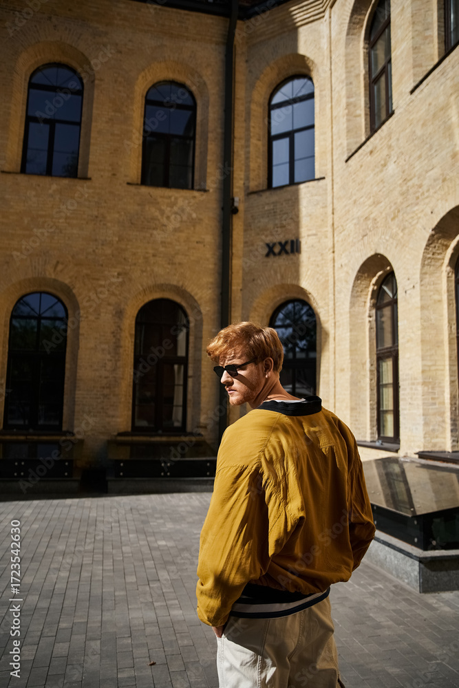 Naklejka premium Stylish young redhead enjoying autumn in an urban courtyard setting