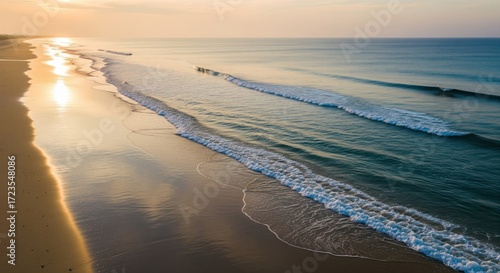 Serene coastal scene featuring gentle waves meeting a sandy beach at sunrise or sunset