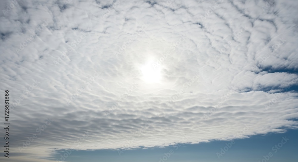 Obraz premium Expansive altocumulus clouds with a radiant sunburst illuminating the atmosphere
