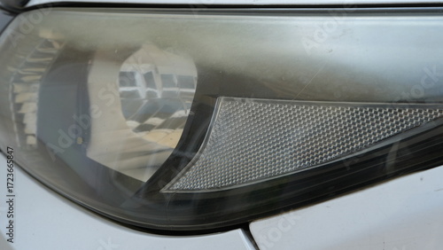 Close-up of aged car headlights, yellowed and foggy, with a dull faded glow that creates a worn-out look.