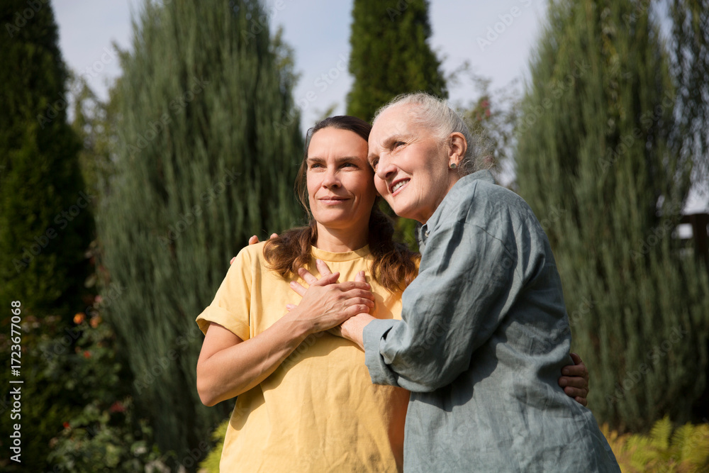 Fototapeta premium an elderly woman hugs her adult daughter near the house in the garden. Deep conversation. emotional intimacy. support in two age generations