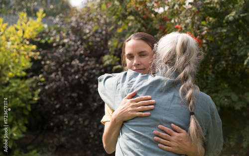 Konstfotografi an elderly woman hugs her adult daughter near the house in the garden