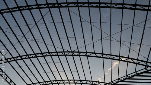 Quadro su tela Steel roof frame structure under construction against a blue sky background