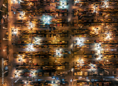 Busy container terminal with colorful cargo boxes illuminated at night.