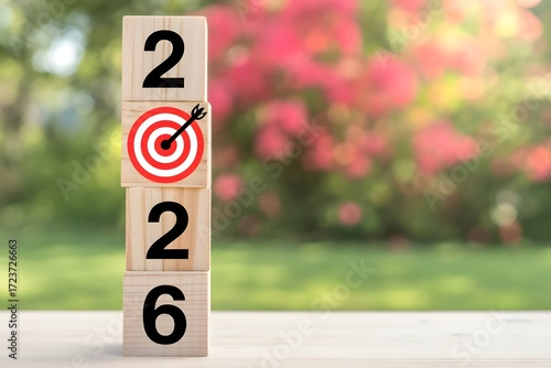 Stacked wooden blocks display the year 2026 with the number 2 featuring a bullseye target and arrow symbolizing successful goal achievement and future aspirations outdoors