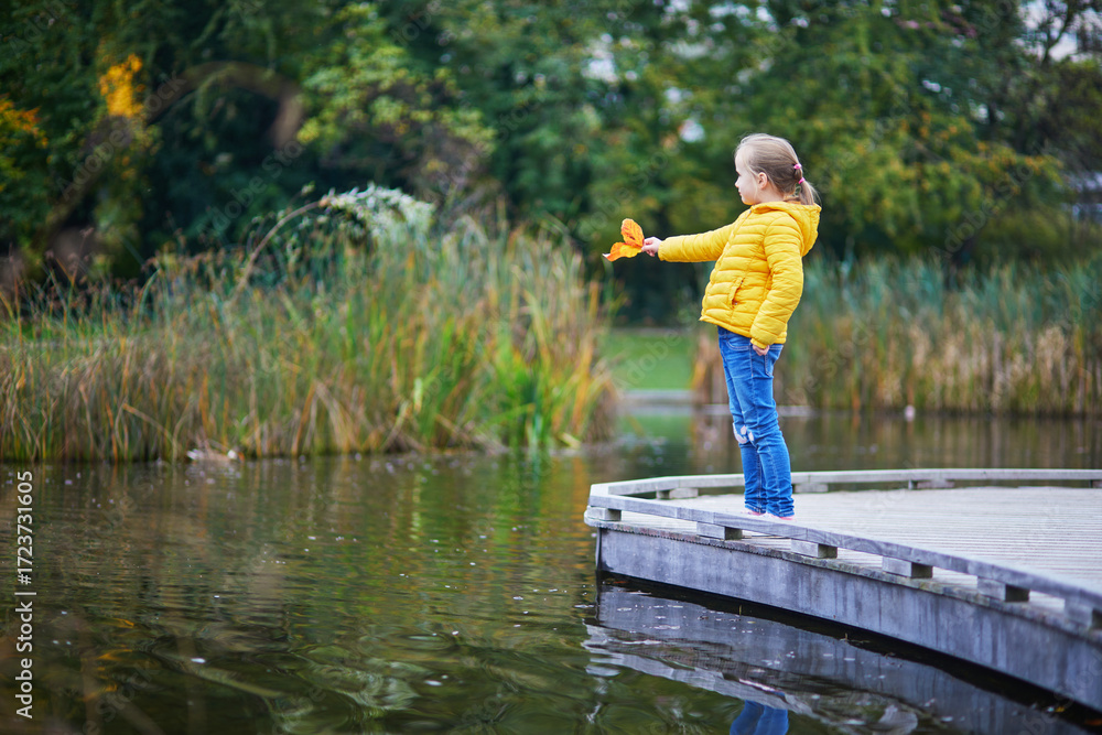 Fototapeta premium Cheerful little girl enjoying her walk in autumn park in Paris, France.