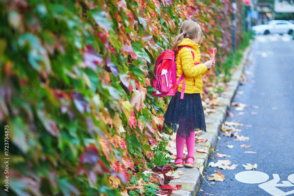 Naklejka premium Cheerful school girl enjoying her walk in autumn park in Paris, France.