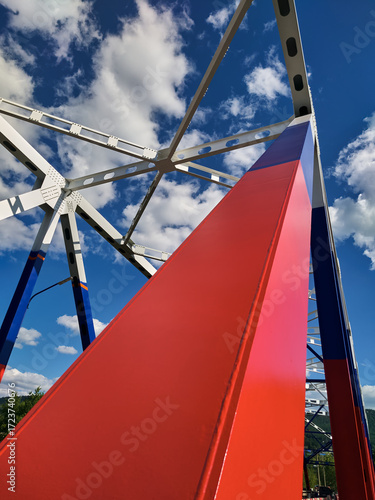 Trusses of the automobile bridge over the river, the geometry of steel beams on the background of the blue sky