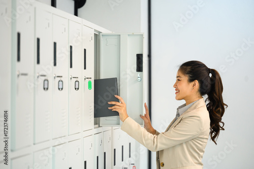Smiling businesswoman organizing documents into office locker