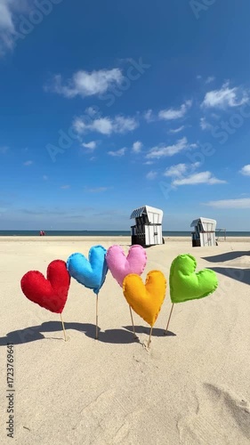 self created Colorful fabric hearts on sticks planted in the sand by the sea in autumn season