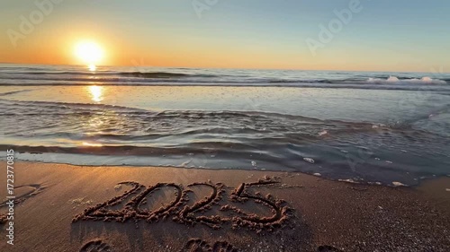 handwritten text of 2025 on a sandy surface at the beach, concept of the New Year, Welcoming the year 2026, Happy New Year. Seashore, waves, sand