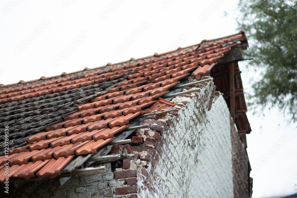 Naklejka premium A broken roof with missing tiles on an abandoned brick house in the countryside.
