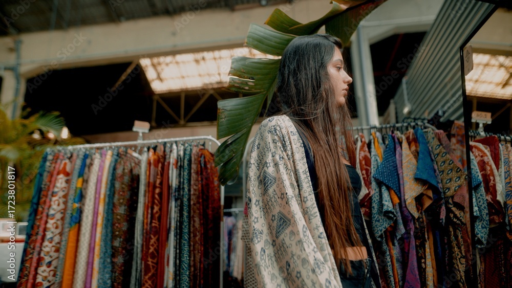 Fototapeta premium A Young Woman Exploring the Vibrant, Colorful Textile Market and Its Craftsmanship