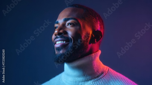 A stylish Black man with a warm smile is illuminated by colorful neon lights.