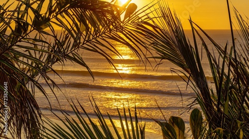 Tropical sunset with golden reflections on calm ocean water and silhouettes of palm trees for serene seascape and travel concept