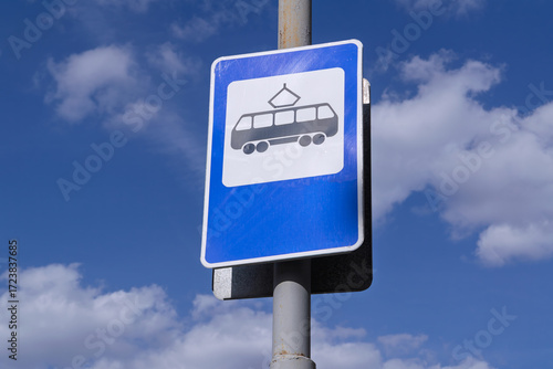 Close-up of a tram stop road sign against a blue sky.