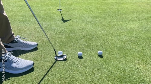 A golf course with a golf ball on the ground and a golf club in the air. The scene is set on a sunny day