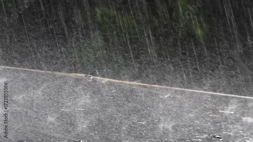 Heavy rain falls on the roof of a gazebo in a garden in slow motion