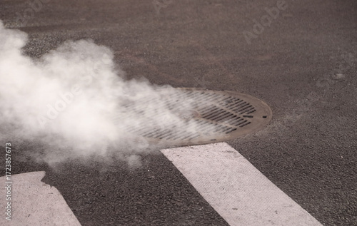 Fotografie smoke coming out of a cast iron manhole cover on a busy city street