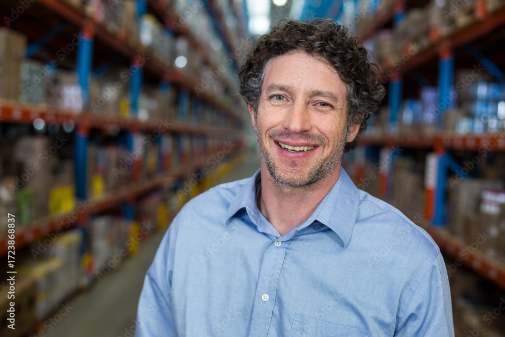 Fototapeta premium Metal shelving units are extending in warehouse aisle, holding boxes toward vanishing point