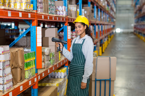 Canvastavla Female warehouse worker using handheld scanner scanning boxes on orange-blue rac