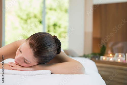 Free Download Woman receiving massage on table in spa room wearing white towel beside lit candles on shelf - GFXLoad