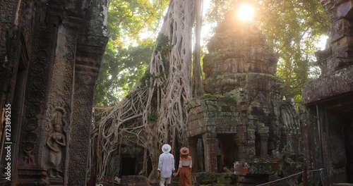 Couple Walking Through Ta Prohm Temple Ruins With Giant Tree Roots At Sunrise