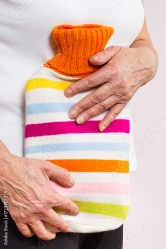 Senior woman with hot water bottle on her stomach. Help with pain in old age