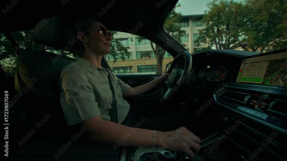 View from the car interior of a woman as she drives around the city. A woman in sunglasses gets into a car, fastens her seat belt and starts driving around the city.