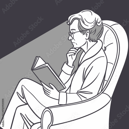 Thoughtful man in glasses reading a book while sitting in a comfortable armchair under a spotlight