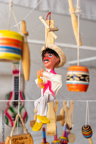 Traditional wooden puppet toy with typical mexican costume, background with typical mexican toys blurred. Guadalajara, Jalisco, México October 1, 2024. balero