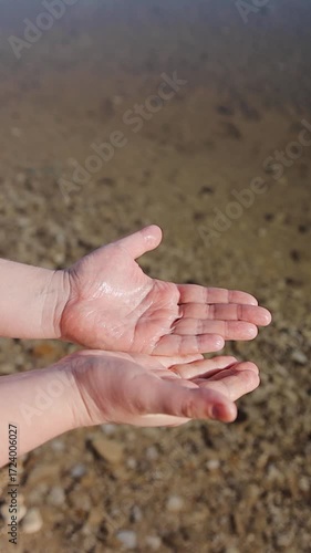Man's palms on the sea water background. On the Dead Sea beachside. Very salty water that's left wonder effect on human skin. Vertical video