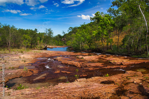 A shallow river with red rocks along the Cascades Walk in the tropical monsoonal rainforest of Litchfield National Park, Northern Territory, Australia
