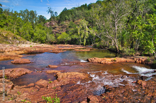 A shallow river with red rocks along the Cascades Walk in the tropical monsoonal rainforest of Litchfield National Park, Northern Territory, Australia
