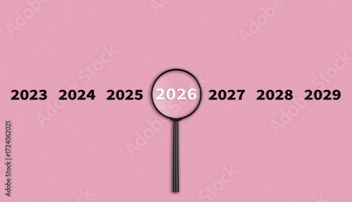 Lens, magnifying glass focusing on the year 2026 on a red background. Financial or stock market strategies and past and future events.