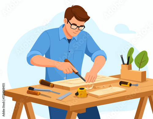 A focused young man wearing glasses carefully chiseling intricate details into a piece of wood on his workbench, surrounded by various woodworking tools.