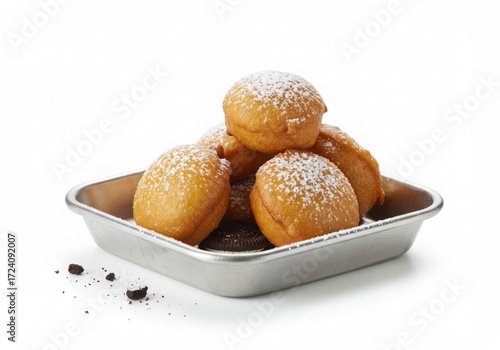Pile of golden fried Oreos dusted with powdered sugar on a tray with crumbs.