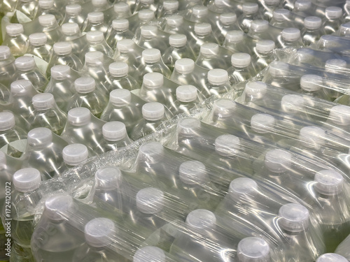 Bulk packaged clear plastic bottles with white caps in rows for distribution