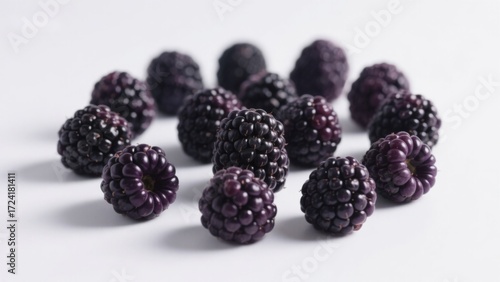 A cluster of fresh blackberries arranged on a white surface