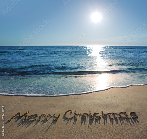 Merry Christmas handwritten on the sea sand.