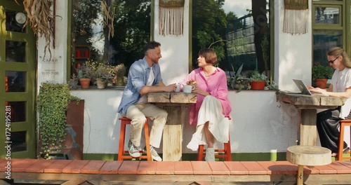 A man and a woman are talking and eating sitting at a table on the cafe terrace.