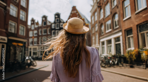 Woman with a straw hat walking through a charming street in Amsterdam