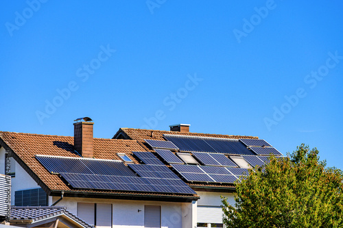 Wohnhäuser mit Solaranlagen zur Erzeugung von Strom und Warmwasser vor blauem Himmel