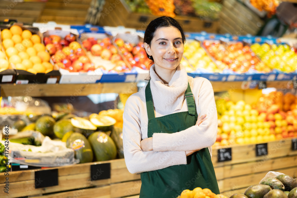 Φωτογραφία Female seller of fruit and vegetable store waits for visitors near counter and greets clients