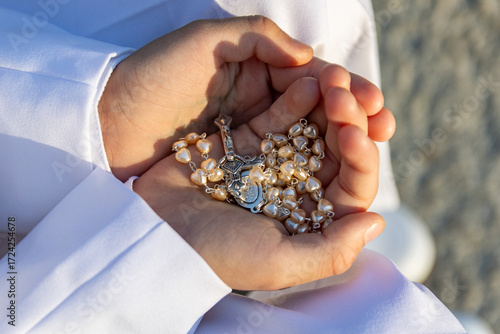 Child Holding Rosary Beads in Hands
